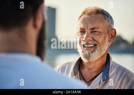 Happy father talking with adult son outdoors Stock Photo