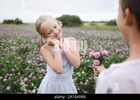 Boy giving a clover flowers to smiling girl Stock Photo