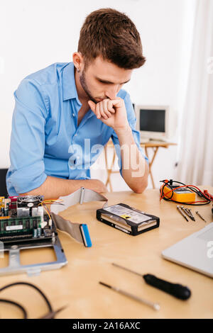 Technician repairing a desktop computer, thinking how to repair the hard drive Stock Photo