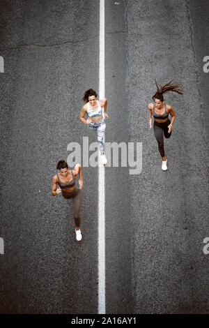 Top view of three sporty young women running on a street Stock Photo