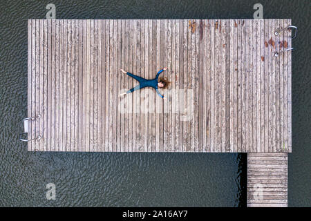 Aerial view of a young female triathlete lying on jetty at a lake Stock Photo