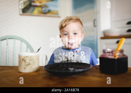 Portrait of cute little boy with blueberry jam in his face Stock Photo