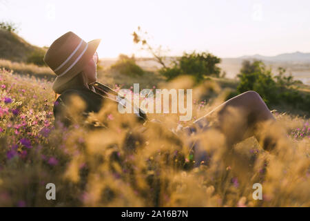 Young woman sitting on meadow at sunset Stock Photo