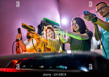 Friends playing and shooting with pistols in an amusement arcade Stock Photo