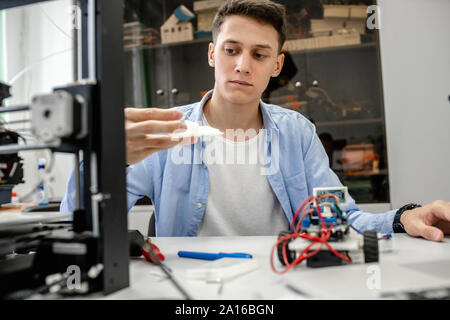 Student setting up 3D printer, using laptop Stock Photo