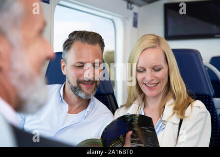 Couple traveling by train, reading magazine Stock Photo