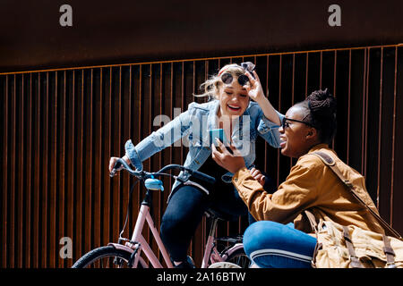 Friends meeting in the city, talking, using smartphone Stock Photo