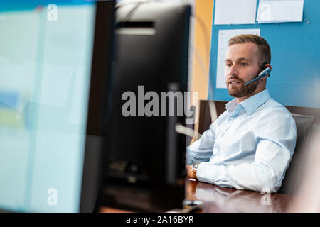 Businessman with headset at desk in office Stock Photo