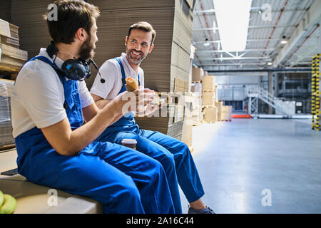 Two happy workers having lunch break in factory Stock Photo