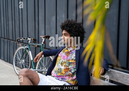 Stylish man with bicycle sitting on a bench Stock Photo