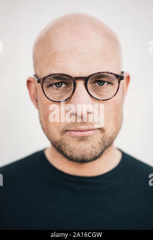 Portrait of serious bald man with beard wearing glasses Stock Photo