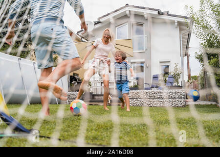 Happy family playing football in garden Stock Photo