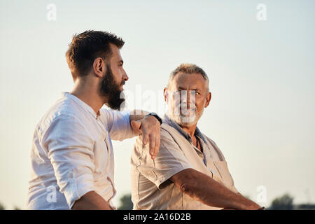 Father and adult son talking outdoors Stock Photo