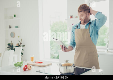Good-wearing tired exhausted man hold gadget in hand look at scr Stock Photo