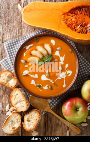 Pumpkin apple puree soup with seeds, yogurt and mint closeup on the table. Vertical top view from above Stock Photo