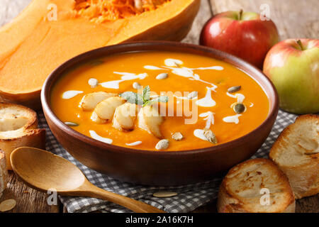 Traditional autumn pumpkin and apple soup with seeds close-up in a bowl on the table. horizontal Stock Photo
