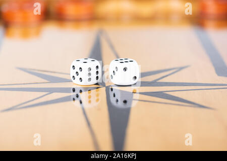 Dice and checkers on a wooden backgammon board. Game dice are reflected on the surface of the backgammon board. Close up. Stock Photo