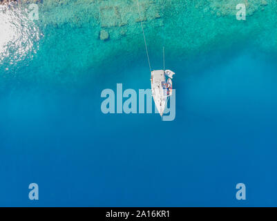 Sailing yacht moored to the shore, a delightful seascape drone photo. Clear blue sea. Stock Photo