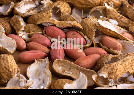heap of raw peeled peanut among shells on the table, closeup Stock Photo