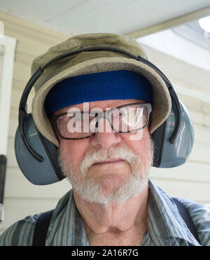Elderly man ready to mow with his earmuffs on. Stock Photo