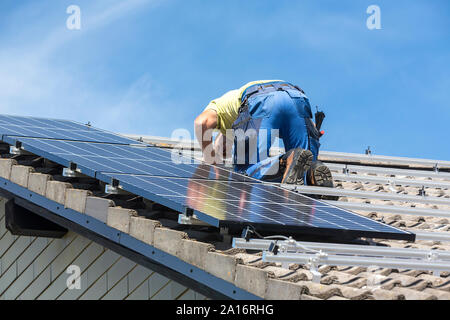 Installing solar photovoltaic panel system. Solar panel technician installing solar panels on roof. Alternative energy ecological concept. Stock Photo