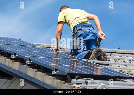 Installing solar photovoltaic panel system. Solar panel technician installing solar panels on roof. Alternative energy ecological concept. Stock Photo