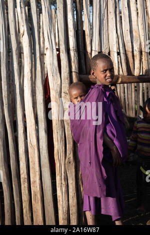 Masai children of Chief Eliedorop tend to younger children and family goats. Stock Photo