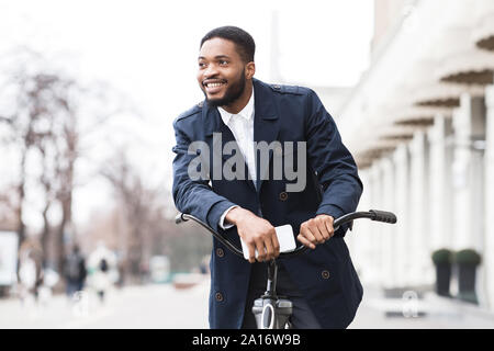 African american man in suit riding on bike to work Stock Photo