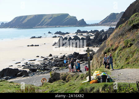 Rubbish collection and plastic collected from the beach at Marloes Sands & family walking on Wales Coastal Path Pembrokeshire UK  KATHY DEWITT Stock Photo
