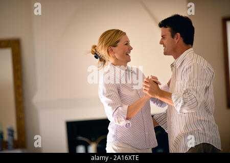Couple dancing playfully in their living room together. Stock Photo
