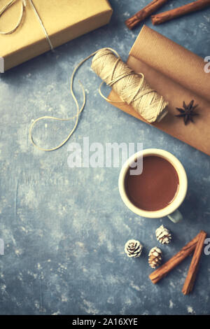 Mug of hot chocolate, spices, gift box and wrapping paper on gray background. Christmas template. Flat lay Stock Photo