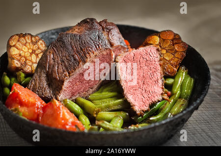 Fried steak with vegetables, in a pan. Selective focus Stock Photo