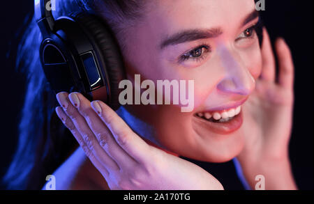 Young woman enjoying music in headset, posing in studio Stock Photo