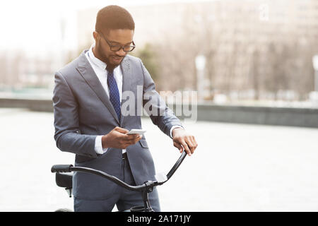 Modern businessman going to office by bike, using phone Stock Photo
