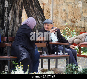 elderly couple chatting on a park bench in Antalya Stock Photo