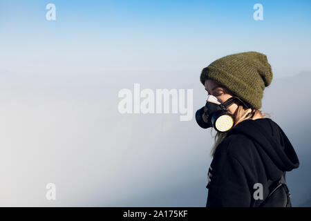 Woman in breath filter mask to protect from toxic gas and poisonous fumes during adventure hike to active volcano Kawah Ijen with crater acid lake Stock Photo