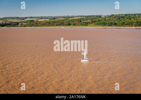 An image of a small yacht on the muddy River Humber taken from the west walkway of the Humber Bridge, East Yorkshire, England. 21 September 2019 Stock Photo