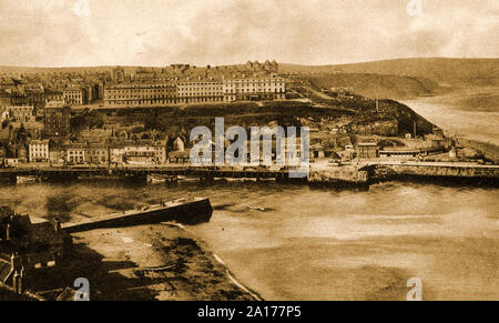 A vintage 1930's  photograph at Whitby, North Yorkshire, showing the west side of the town, the west pier and West Cliff with the Royal Hotel (Right of Kirby's Hotel)  prominent at the top of Khyber Pass and the towers of the Metropole Hotel in the distance. (In the foreground is Tate Hill Sands, featured in the Dracula novel by Bram Stoker) Stock Photo