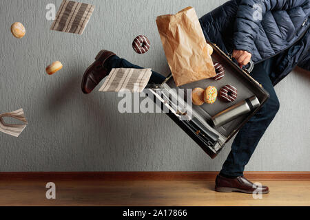 The man runs to the office: he is late and loses the contents of his briefcase. In case thermos, doughnuts and napkins. Stock Photo