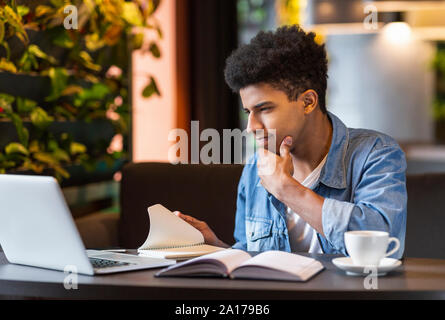 Hard-working student making homework, using laptop at cafe Stock Photo