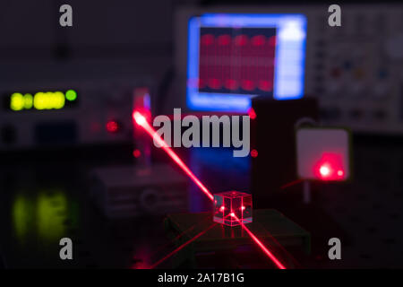 Experiment in optic lab with laser device. Red laser on optical table in physics laboratory Stock Photo