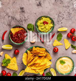 Mexican food background: guacamole, salsa, cheesy sauces with nachos, top view. Stock Photo