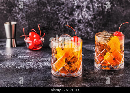 Old fashioned cocktail with cherries and orange twist, selective focus. Stock Photo