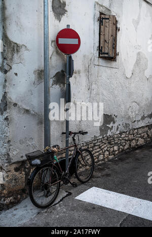 Old Bicycle Locked With Chain On Pole In Front Of Old House Stock Photo