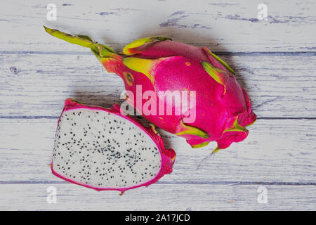 dragon fruit half beside a pink dragon fruit on white wooden background Stock Photo