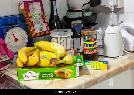 WELWYN GARDEN CITY, UK - SEPTEMBER 23, 2019: Various food items and pain killers on a messy kitchen worktop Stock Photo