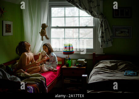 Two children in pajamas play with stuffed animals in a bedroom Stock Photo