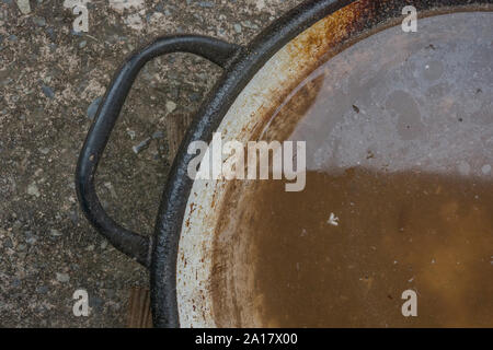 Old iron pan full of dirty standing water Stock Photo