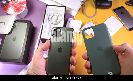 Paris, France - Sep 20, 2019: Man hand unboxing unpacking new latest Apple Computers iPhone 11 Pro and 11 Pro Max smartphone triple-lens camera, silicon green case and clear case Stock Photo