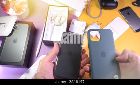 Paris, France - Sep 20, 2019: Man hand unboxing unpacking new latest Apple Computers iPhone 11 Pro and 11 Pro Max smartphone triple-lens camera comparing silicon green case and clear case Stock Photo